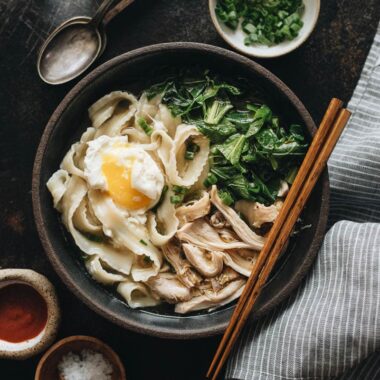 One bowl of Instant Pot chicken noodle soup with Sriracha and salt on the side